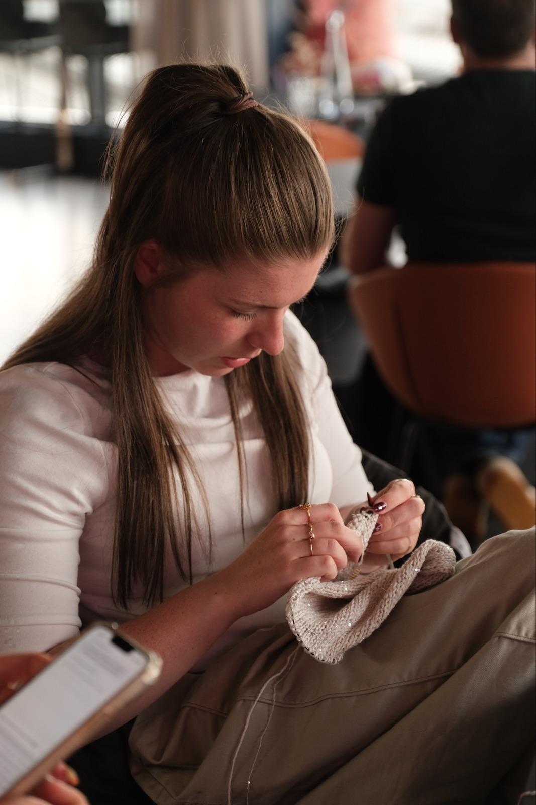 Someone knitting at a table at Make Stuff Club